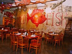 an empty restaurant with tables and chairs in front of a fish painted on the wall