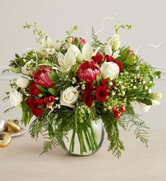 a vase filled with red and white flowers on top of a table next to gold shoes