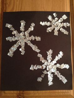 a piece of tin foil is cut into snowflakes and placed on a table