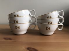 four coffee cups with arrows on them sitting on a wooden table next to a wall