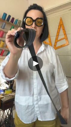 a woman holding a pair of scissors in front of her face while standing next to a sewing machine