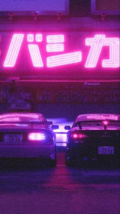 two cars parked in front of a neon sign