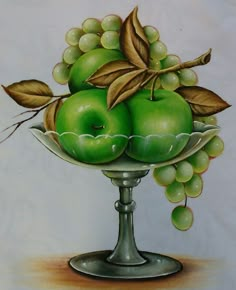 a painting of green apples and grapes in a silver bowl with leaves on the rim