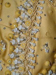 a yellow dress with buttons and beads on it