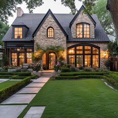 a large brick house with lots of windows and landscaping in front of it at dusk