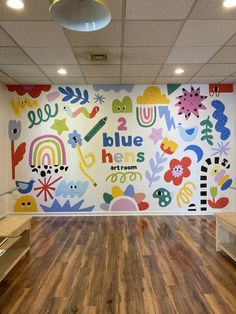 an empty room with painted murals on the wall and wooden floors in front of it