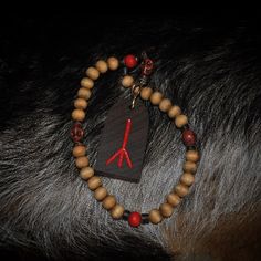 a wooden beaded bracelet with red beads and an arrow on the end is attached to a horse's head