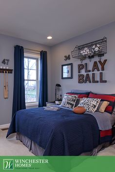 a bed room with a neatly made bed and pictures on the wall above it that says play ball