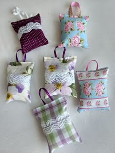 four small purses are lined up on the bed with flowers and lace around them