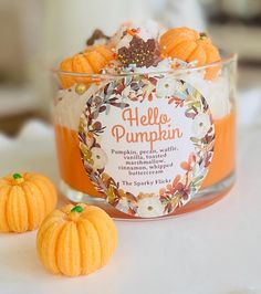 two small pumpkins sitting on top of a table next to a jar of jelly