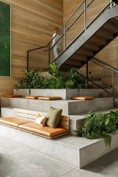 an indoor area with stairs, plants and couches on the concrete floor next to it