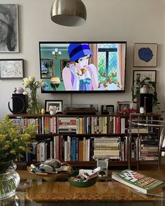 there is a television that is on in the living room with bookshelves and vases