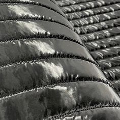 black and white photograph of shiny material on the back of a car seat cover that is folded over