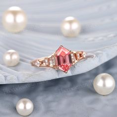 a pink tourmaline and diamond ring sitting on top of pearl pearls in the background