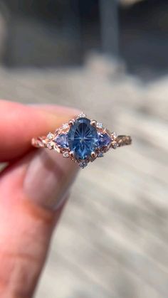 a person holding a ring with a blue stone in it