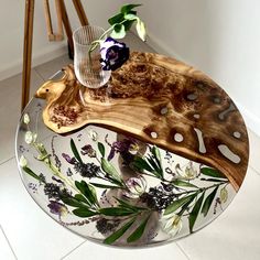 a glass plate with flowers on it sitting on a white tile floor next to a vase