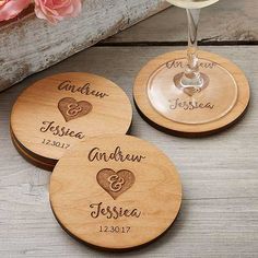 three personalized wooden coasters with wine glasses and flowers in front of them on a table