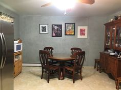 a dinning room table and chairs in front of a refrigerator with pictures on the wall