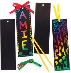 three black bookmarks with colorful writing on them and two yellow straws next to each other