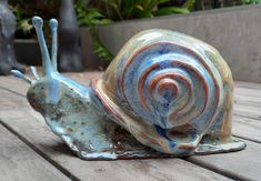 a ceramic snail sitting on top of a wooden table