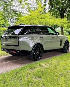 a range rover parked on the side of a road in front of some green trees