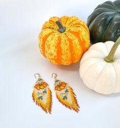 two pumpkins, one with an angel wing and the other with a beaded earring