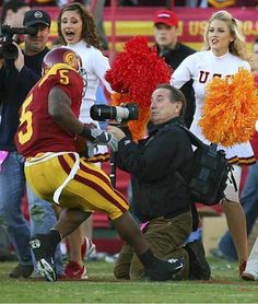 a football player holding a camera and some cheerleaders