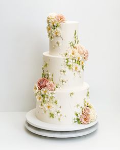 a three tiered wedding cake with flowers on the top and bottom, sitting on a plate