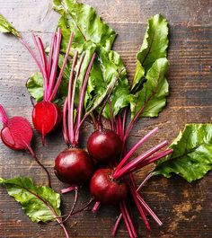 radishes with green leaves and red stems on a wooden surface