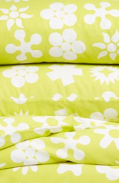 a green and white bed spread with flower designs on the sheets, pillows and pillowcases