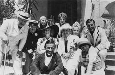 black and white photograph of men and women in hats posing for a group photo on steps