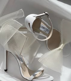 a pair of white high heeled shoes with bows