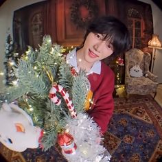 a young man holding a christmas tree in his hands