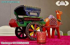 a colorful horse drawn carriage sitting on top of a pink table cloth next to a cup