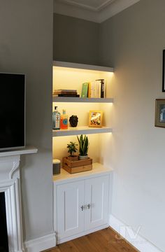 a living room with white shelves and a television mounted on it's side wall