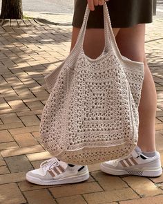 a woman carrying a crocheted bag on her feet