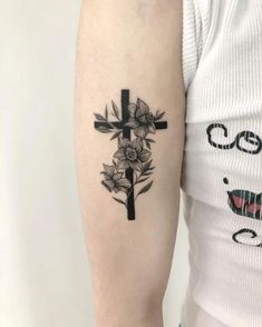 a cross and flowers tattoo on the arm