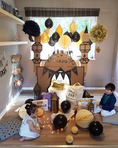 two young children sitting on the floor in front of a birthday cake and other decorations