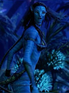 a woman with blue skin and braids holding a snake in her hand while walking through the jungle