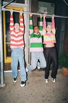 three young men are hanging upside down in front of a building