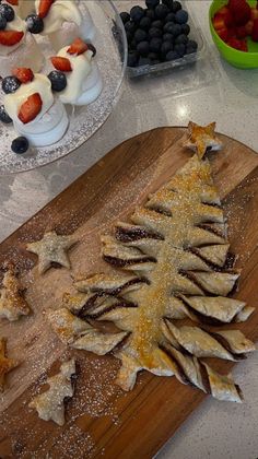 a wooden cutting board topped with fruit and pastries on top of a white counter