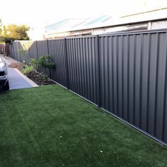 a car is parked in front of a metal fence and green grass on the sidewalk