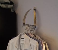 a white shirt hanging on a clothes rack in a room next to a black dresser