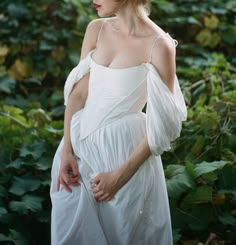 a woman in a white dress is posing for the camera with her hands on her hips