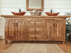 a bathroom vanity with two sinks and a mirror on the wall above it, in front of a potted plant