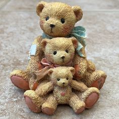 two brown teddy bears sitting next to each other on the ground and one is wearing a blue bow