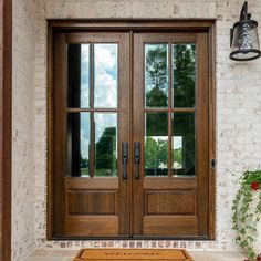 the front door to a house with two large wooden doors and sidelights on either side