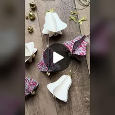 several pieces of paper with bells attached to them on a wooden floor next to christmas ornaments