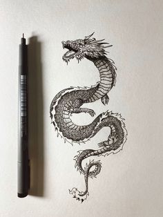 a drawing of a dragon on paper next to a marker and pen with the letter s in it