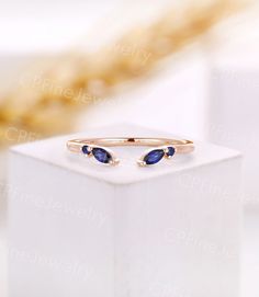 a gold ring with two blue stones on it sitting on top of a white box